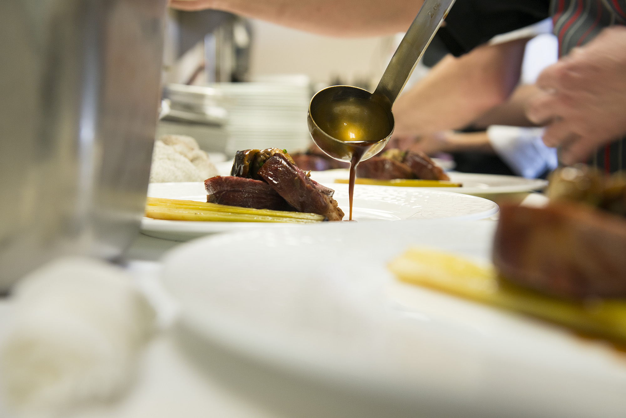 chef pouring gravy over beef dish