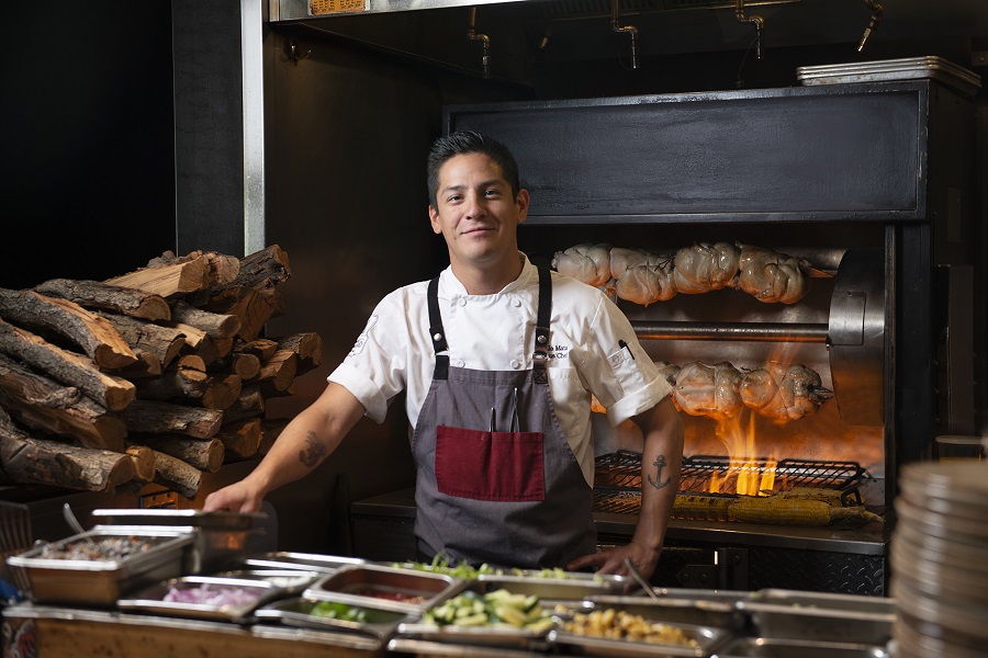 chef roasting meet and smiling at camera